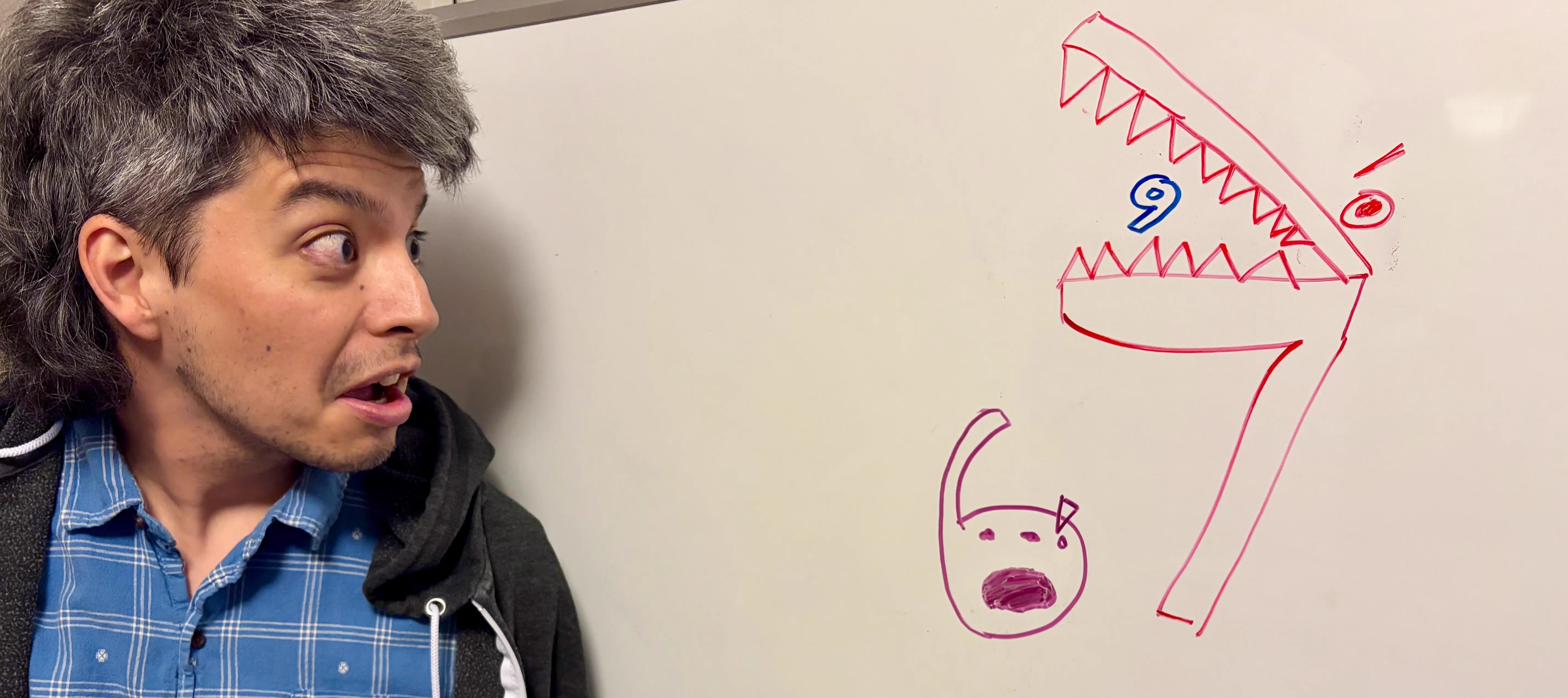 Erik at a whiteboard with playful number characters drawn on it